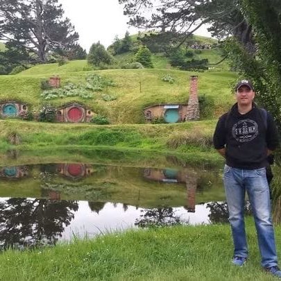 David García-Carazo en Hobbiton, con las casas hobbit y el lago detrás, en Nueva Zelanda