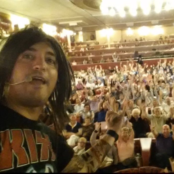 David in a rock costume during a show, with the theatre packed behind him