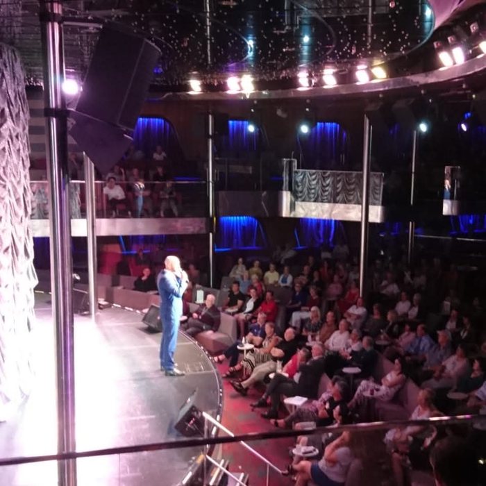 David alone on stage, seen from the balcony, with a full theatre